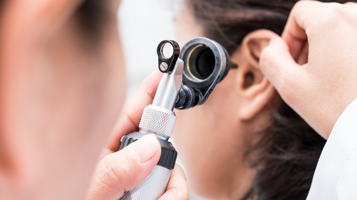  Otolaryngologist looking with a medical device an ear - Professionals